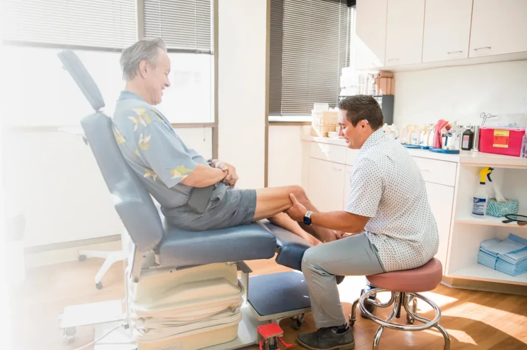 Dr. Paul Morton examines a senior patient's knee in a bright exam room at his Honolulu clinic.