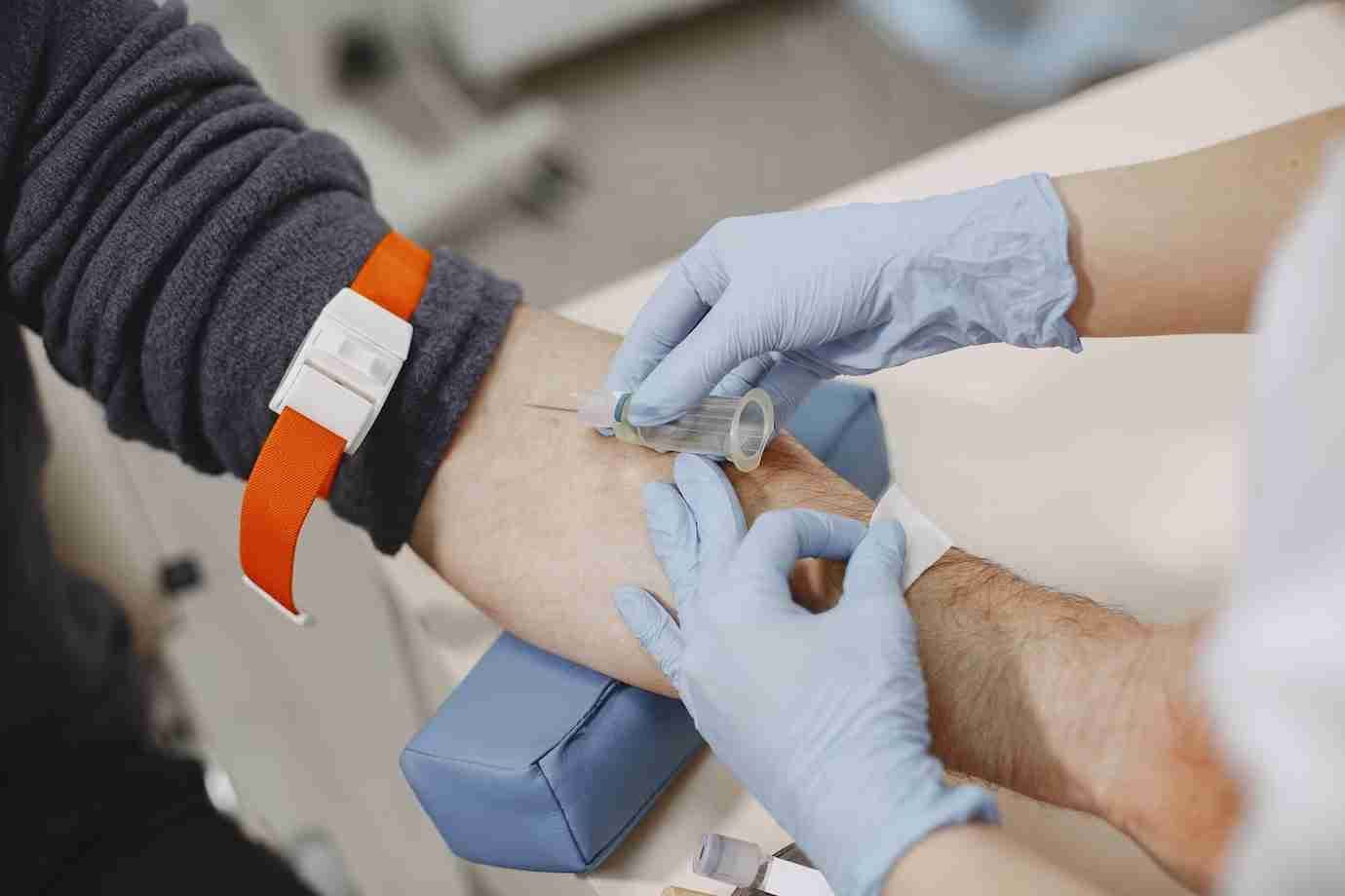 A gloved clinician draws a blood sample from a patient's arm, the first step in preparing platelet-rich plasma.