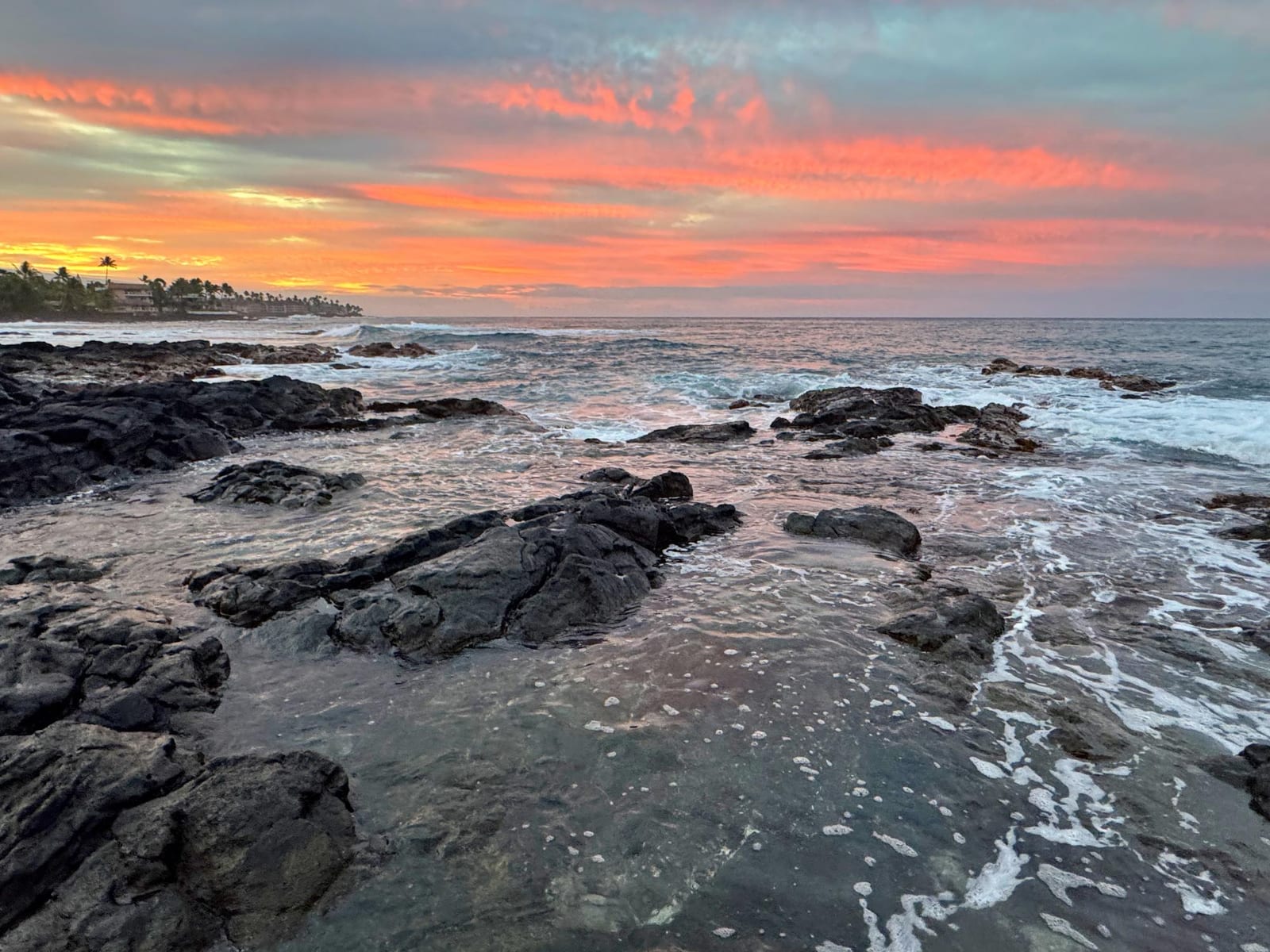 Sunset over the rocky lava-rock shoreline of Kona on Hawai‘i Island.