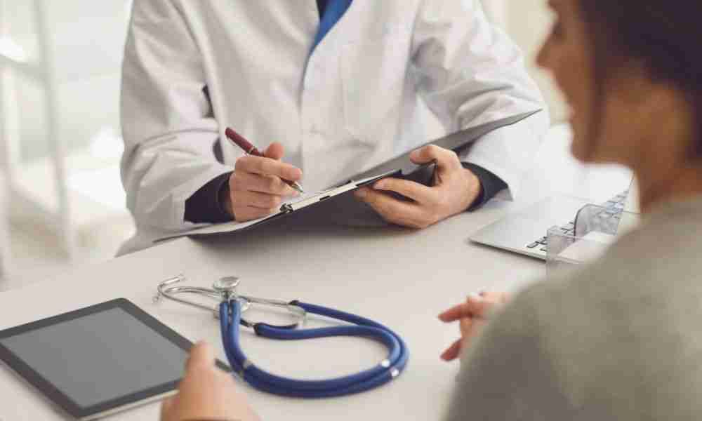 Doctor reviewing joint replacement paperwork and insurance costs with a patient during an office consultation.
