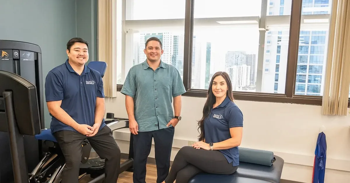 PB&J Physical Therapy team members in the Honolulu clinic gym with downtown views behind them.